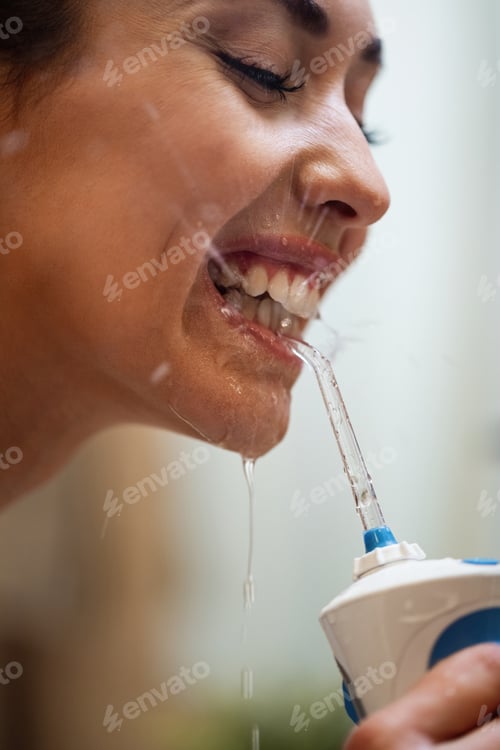 Preview: Close-up of woman cleaning teeth with dental water flosser.