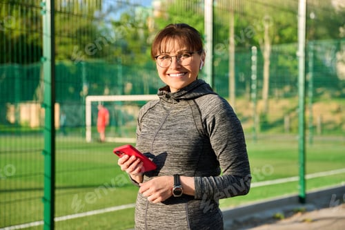 Preview: Portrait of smiling middle aged woman looking at camera at sports outdoor stadium