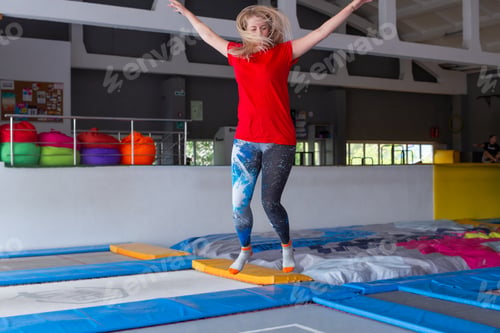 Preview: Fitness, fun, leisure and sport activity concept - Young happy woman jumping on a trampoline indoors