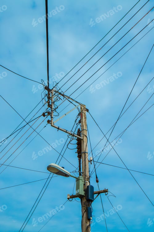 Preview: Vertical shot of street lamp on a wooden pole with high voltage power lines