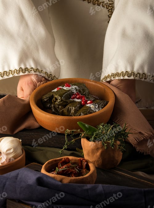 Preview: Photo of woman's hands holding a plate of stuffed grape leaves with ground meat and pomegranate