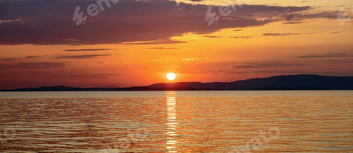 Preview: Sunset over Aegean Sea. Greece. Golden reflection on rippled ocean water. Dark land and colorful sky