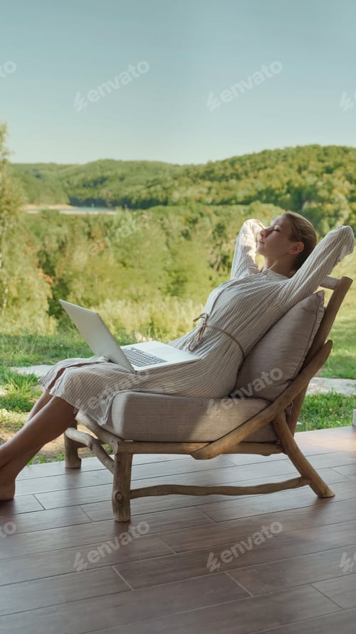 Preview: Young woman freelancer sitting on a wooden chair relaxing after work