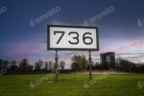 Preview: Large 736 sign on a field near a city during sunset