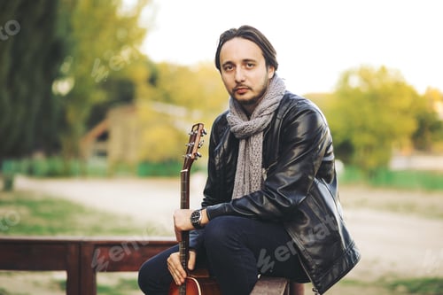 Preview: Young man playing on guitar at the lake