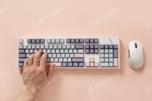 Preview: Mans hand typing on keyboard on pink background. View from above. Flat lay.
