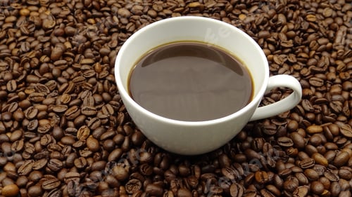 Preview: A cup of black coffee over roasted coffee beans