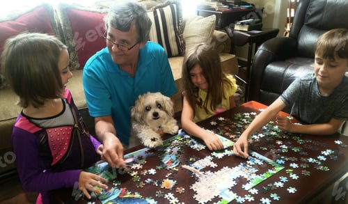Preview: Family fun with gen z kids and cute pet in home sweet home having fun working a puzzle together.