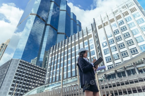 Preview: Expert female architect reviews Skytrain site, cross referencing blueprint for project approval.
