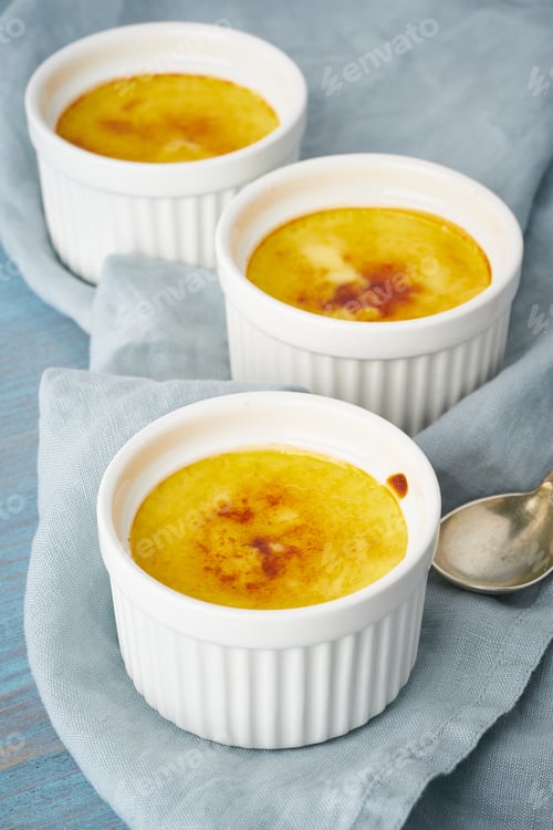 Preview: Crema catalana, Spanish dessert in three ramekin on blue table, vertical