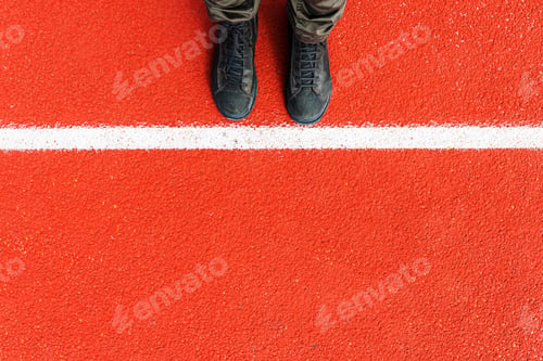 Preview: Top view of dirty male boots standing next to the white line, afraid and hesitating to cross it