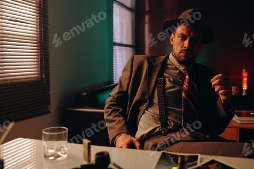 Preview: Confident man in formalwear sitting by workplace in dark office