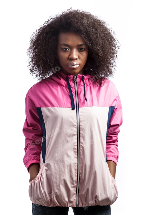 Preview: Young curly brown-haired girl dressed in the pink sport jacket stands at the white background in the