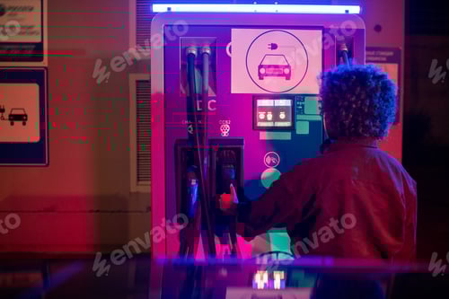 Preview: Back of young woman taking pump for charging her car