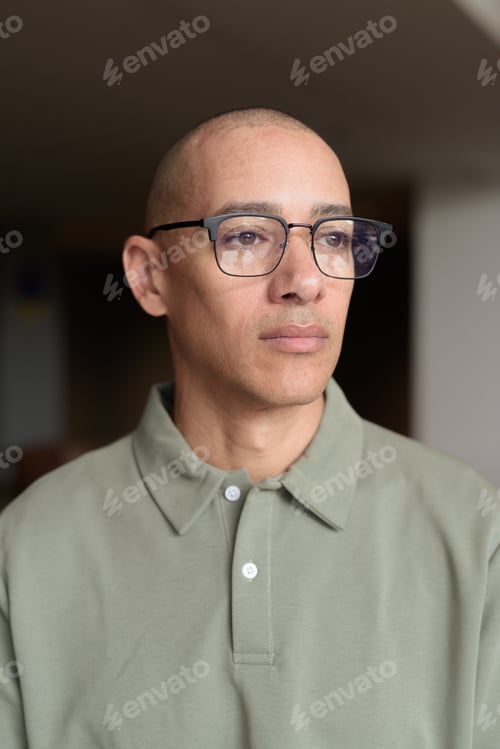 Preview: Bald Hispanic man in hotel lobby with eyeglasses, stylish confident portrait in casual setting