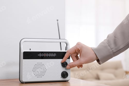 Preview: Woman turning volume knob on radio at home, closeup