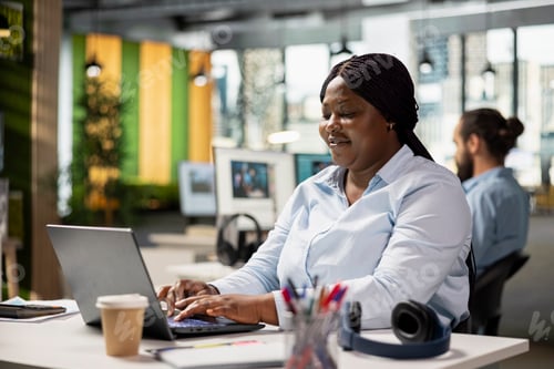 Preview: African american staff working on laptop in modern corporate workspace