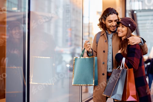 Preview: Happy couple talking while looking at store windows and shopping in the city.