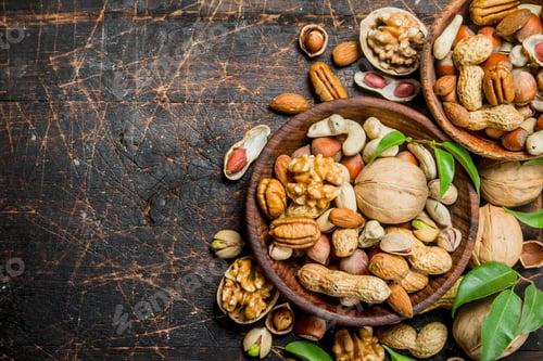 Preview: Different types of nuts in bowls with green leaves.
