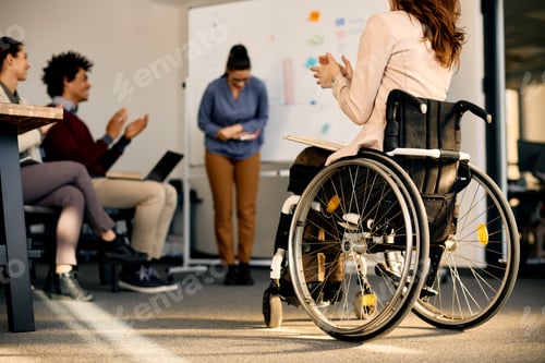 Preview: Back view of businesswoman with disability applauding during a seminar in board room.