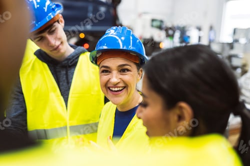 Preview: work staff with protective helmet in a meeting in the factory - focus on senior smiling woman -