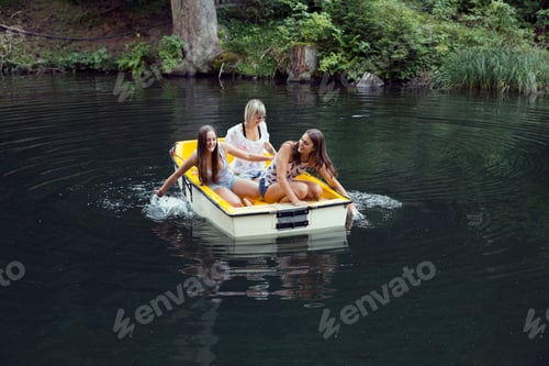Preview: Three adult female friends hand paddling rowing boat on lake, Sattelbergalm, Tirol, Austria
