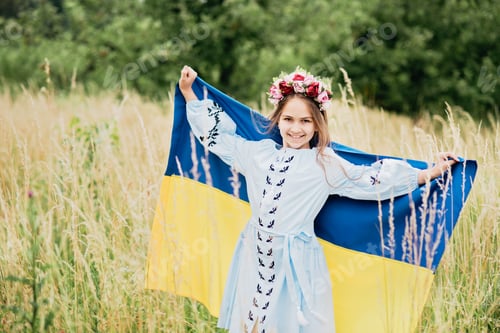 Preview: Ukrainian child girl in embroidered shirt vyshyvanka with yellow and blue flag of Ukraine in field.