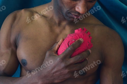 Preview: fit young african american black muscular man holding a heart shaped object depict emotion and love