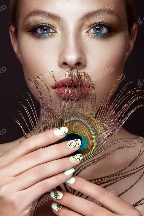 Preview: Beautiful girl with bright colored makeup and peacock feather on her face. Beauty face. Close-up