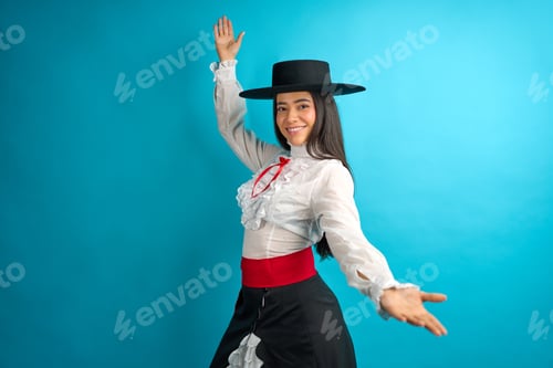 Preview: young latina woman arms outstretched proudly wearing a traditional chilean huasa dress