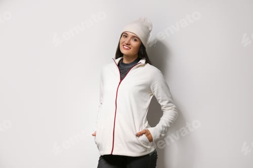 Preview: Woman wearing fleece jacket and hat on light grey background. Winter sport clothes