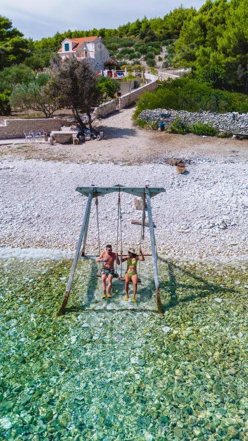 Preview: Couple enjoying a serene swing by the crystal-clear waters of Brac Island, Croatia