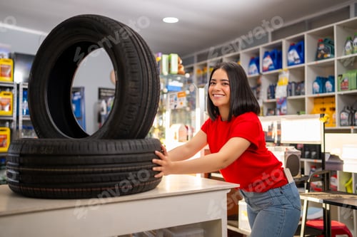 Preview: Smiling woman with new vehicle tires in an automotive repair and retail shop
