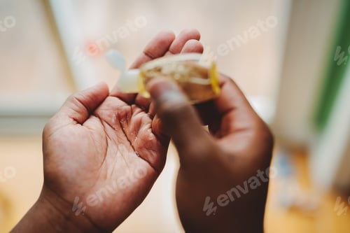 Preview: African-American men at home practicing good hygiene by using hand sanitizer