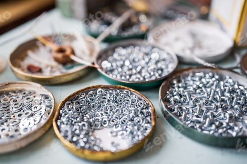 Preview: Small metal nuts bolts and a wrench lie on the work table of the assembler