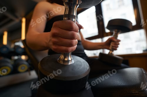 Preview: Female athlete performing seated dumbbell exercise at gym