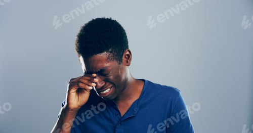 Preview: Sad, black man and crying with mistake, breakup or pain in studio for mental breakdown on a gray ba