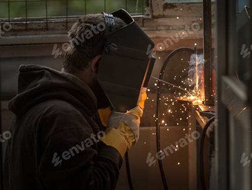 Preview: a man saws a metal profile with a grinder, sparks fly.
