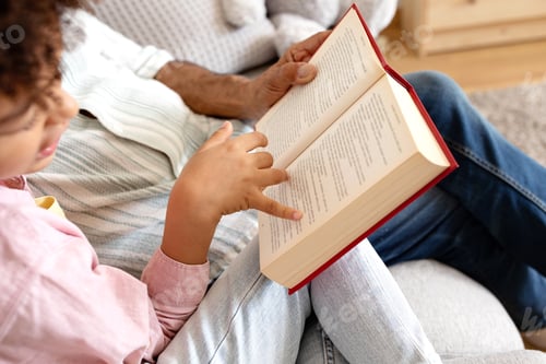 Vista previa: Cropped of senior man and boy reading book at home