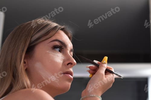 Preview: Young woman, teenage girl is applying make up in a bathroom, getting ready to go out