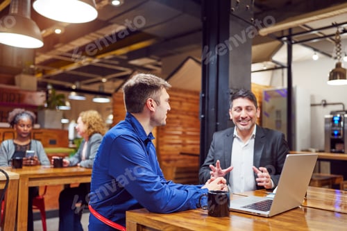 Preview: portrait two businessman sitting indoors drinking coffee talking discussing