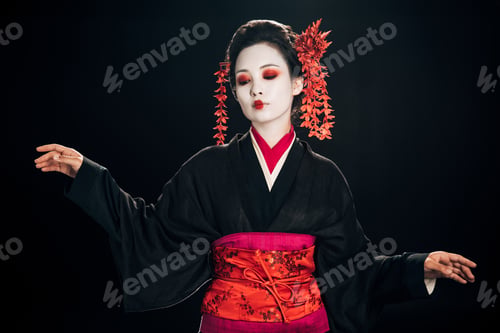Preview: beautiful geisha in black and red kimono and flowers in hair looking down and gesturing isolated on