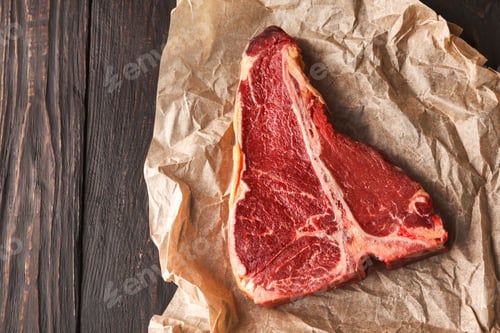 Preview: Raw t-bone steak on craft papper on dark background
