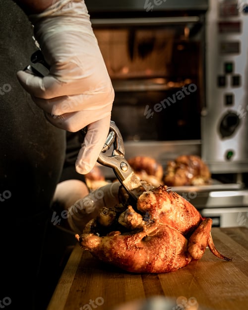 Preview: Chef cutting roasted chicken in professional rotisserie kitchen