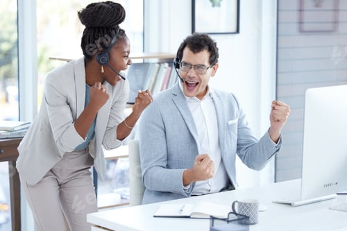Preview: Shot of two young call centre agents cheering while working in an office