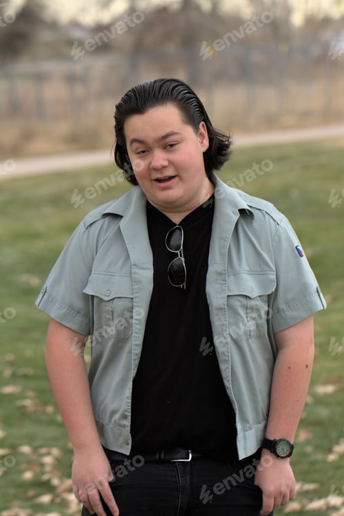 Preview: Young adult Caucasian male standing confidently in a lush green meadow