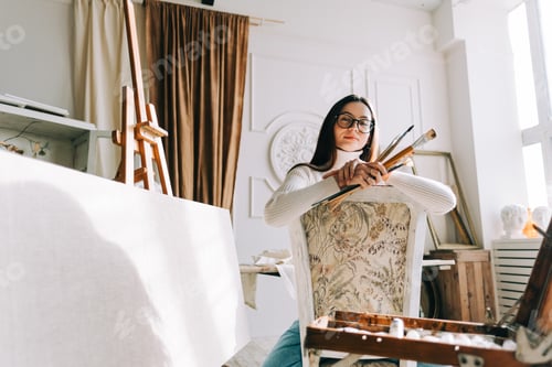 Preview: Female Artist Poses with Brushes in Studio