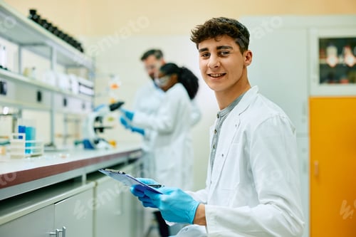 Preview: Young happy scientist working on new research in laboratory and looking at camera.