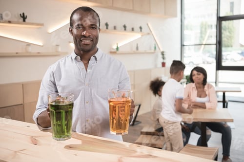 Visualização: homem afro com potes de bebidas e família desfocada no fundo