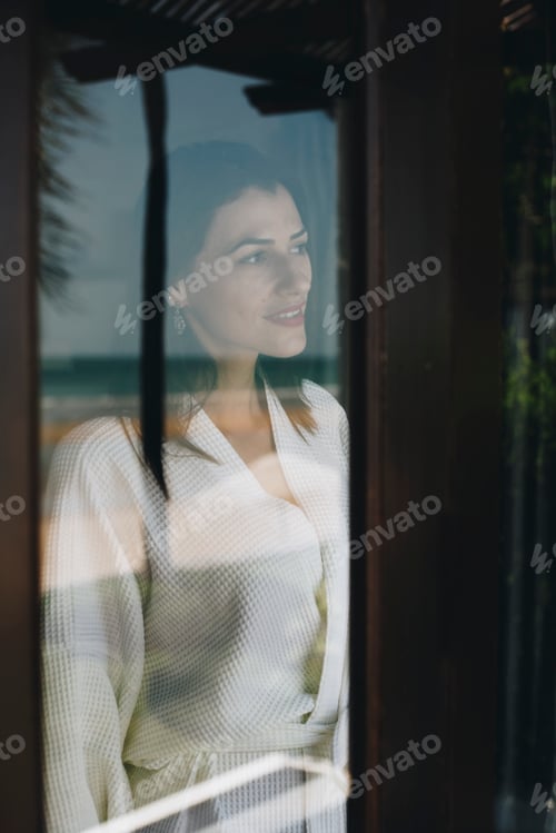 Preview: Woman looking out her hotel room window